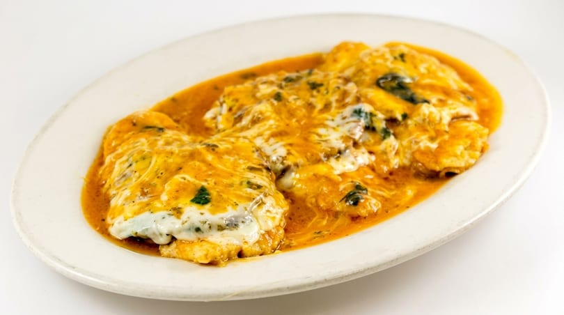 Chicken parmesan with melted cheese and red sauce on a white oval plate.